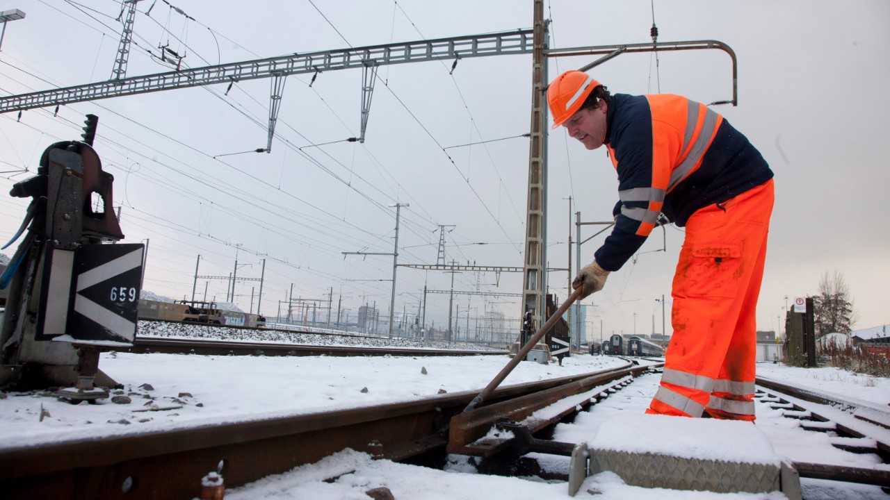 Die Weichen werden von einem Mitarbeiter manuell von Eis befreit.